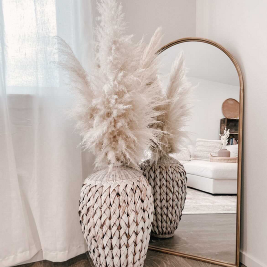 Dried Pampas Grass Bouquet in a rattan floor vase next to an arch mirror in a boho home aesthetic home